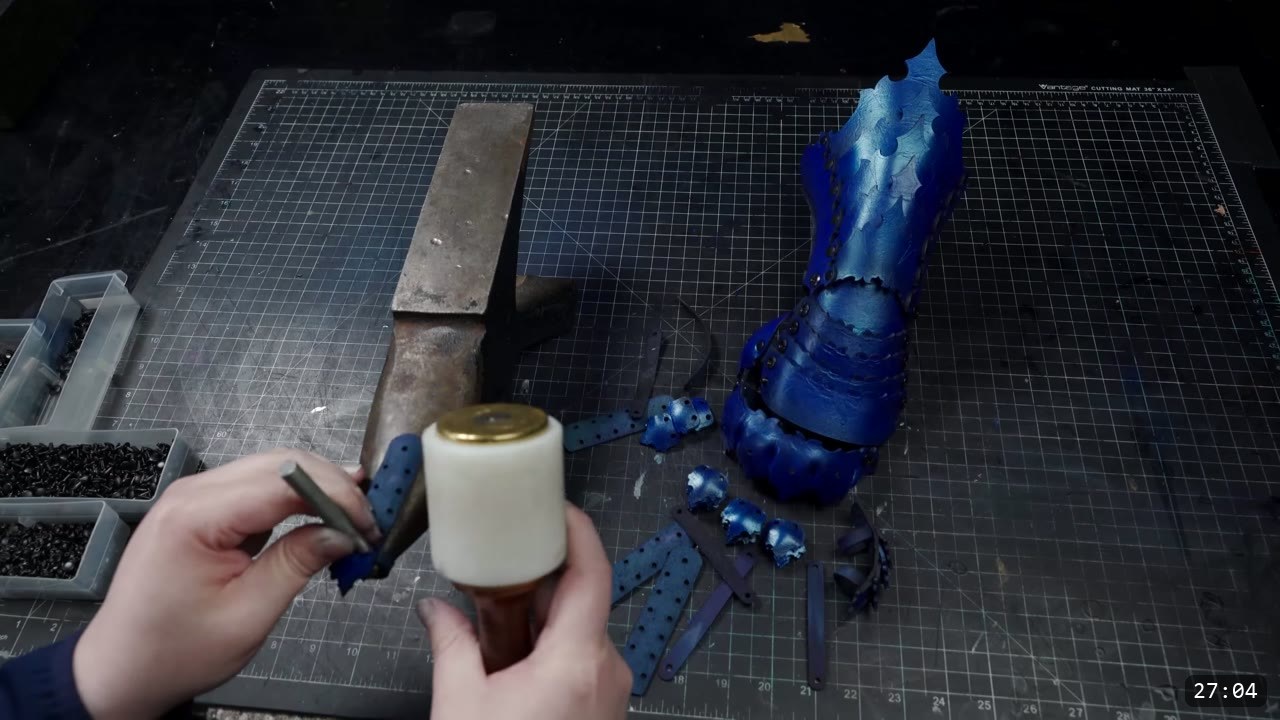Articulating Leather Gauntlets Build Guide: Imperial Knight, Cut to Finish 10 a tall blue articulated gauntlet cuff standing on the cutting mat with loose finger scales nearby and hands holding a poly mallet and a center punch
