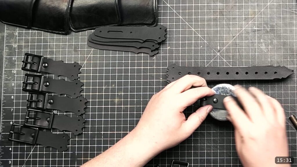 setting black double-cap rivets to join roller buckles to the finished black buckle straps