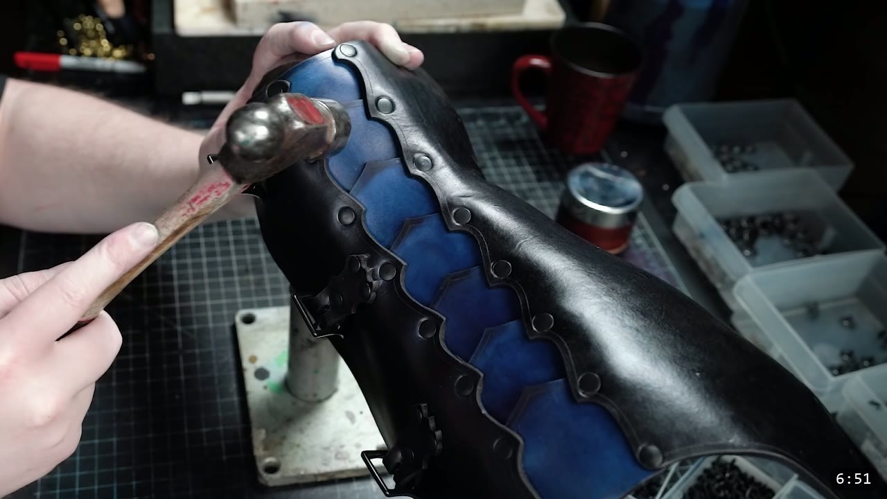 Leather Greaves Build Guide: Imperial Leg Armor from a Flat Pattern 8 a formed two-tone greave, black with blue lamellar scallops, being smoothed with a hammer over a rounded stake