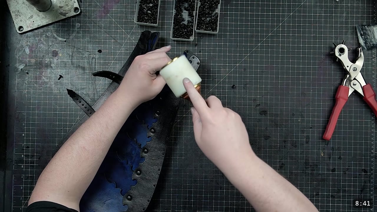 Leather Greaves Build Guide: Imperial Leg Armor from a Flat Pattern 10 a white poly mallet tapping rivets along the black and blue greave back section on a cutting mat