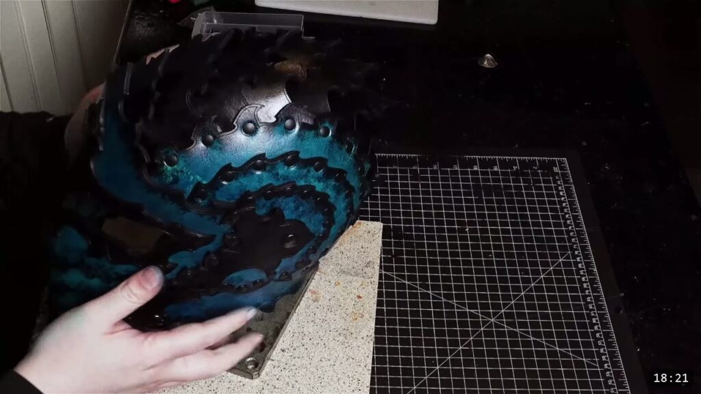 the finished leather Imperial Knight helmet with a dark blue-black gradient finish, scalloped riveted edges, held over a granite slab