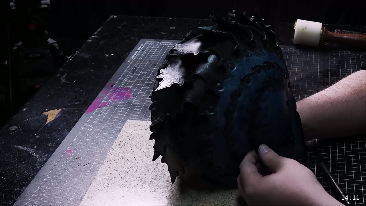 hands holding the dark-dyed helmet core while fitting a lighter trim piece to check alignment before marking holes