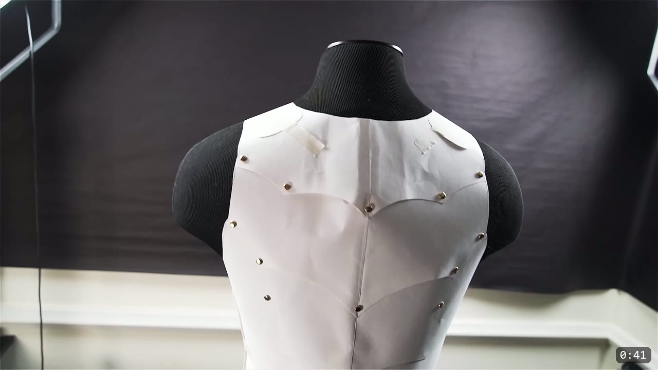 a white paper armor mock-up pinned to a black dress form to check fit before cutting any leather