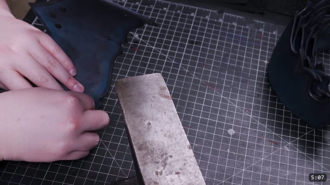 setting hardware on a black-dyed plate against a small steel bar anvil on the cutting mat, more dyed lames nearby