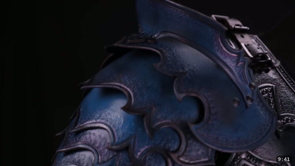 the finished blue-black Imperial pauldron mounted on the shoulder, articulating scalloped lames and a buckle strap at the collar, dark background