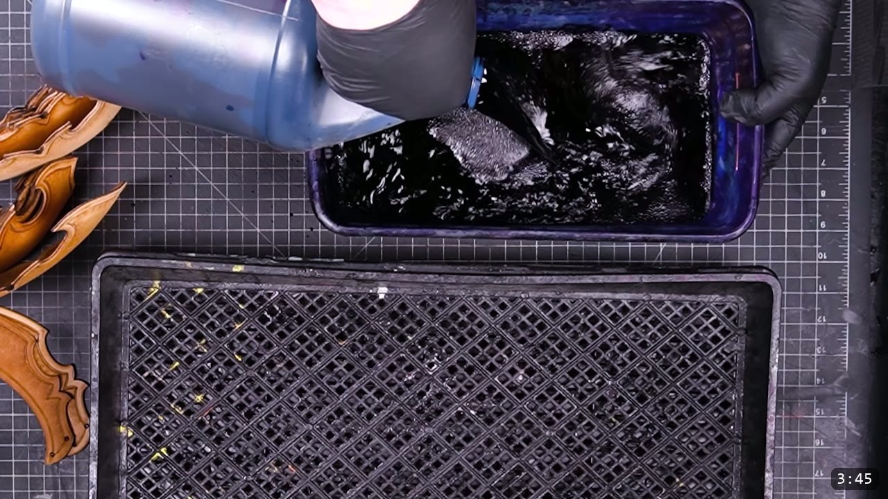 pouring dark dye into a tray to immersion-dye a lame, undyed tan lames waiting at left over a graded drip tray