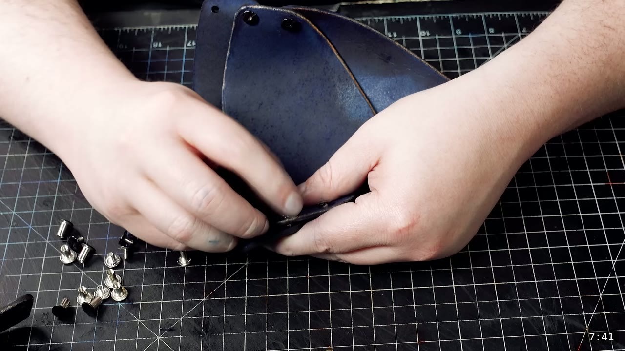 setting silver Chicago screws into the deep-blue articulated sabaton, loose screw posts and caps on the mat