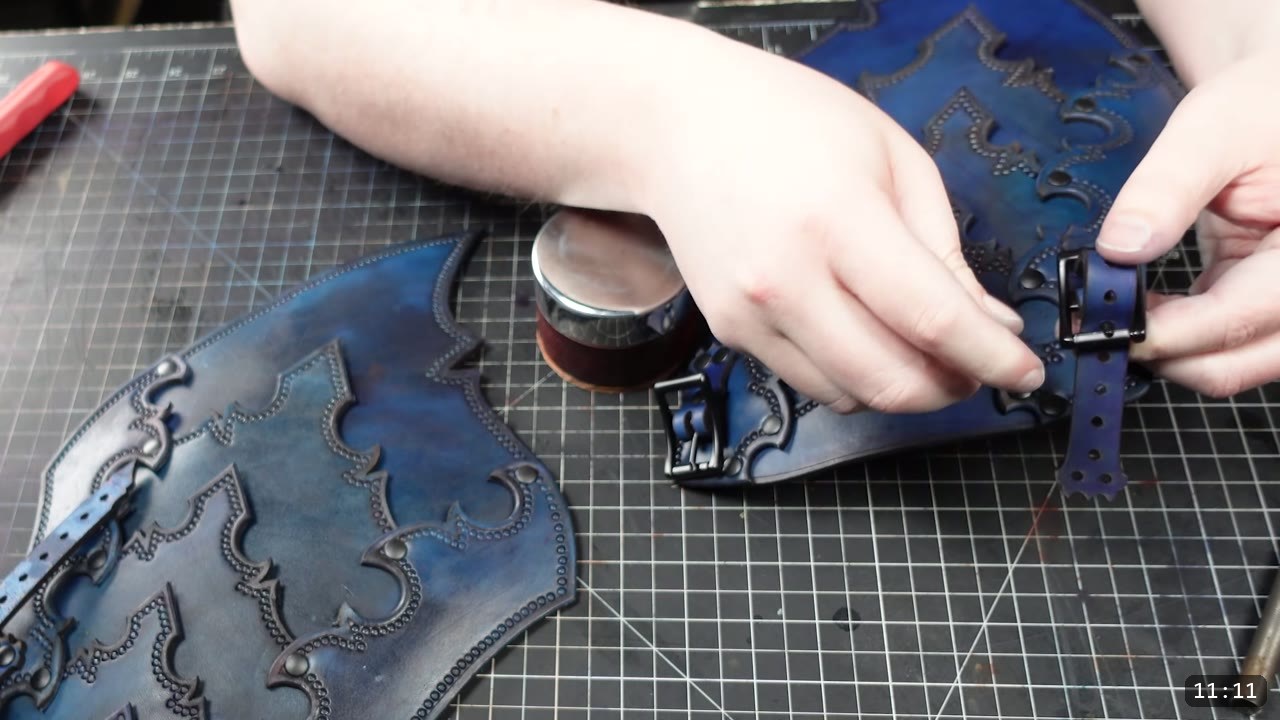Imperial Knight Tassets Build Guide: Leather Hip Armor from a Flat Pattern 12 hands fitting a blue leather buckle strap with a black buckle to a finished blue tasset assembly, a tin of finish on the bench
