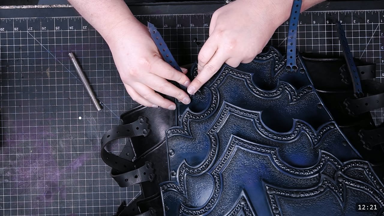 Imperial Knight Tassets Build Guide: Leather Hip Armor from a Flat Pattern 13 hands feeding a punched blue strap to attach the tassets to a large tooled blue Imperial Knight breastplate