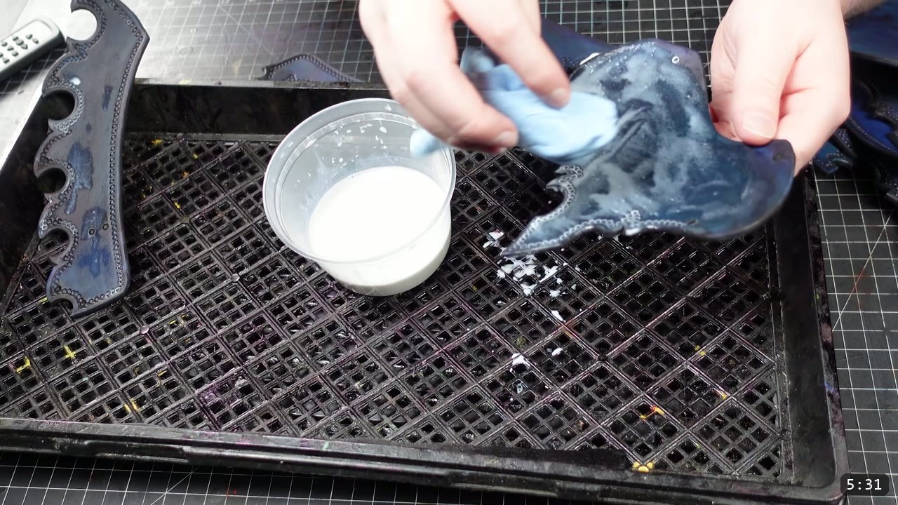 Imperial Knight Tassets Build Guide: Leather Hip Armor from a Flat Pattern 9 gloved hands buffing a dyed blue tasset plate over a drip tray, a cup of finish beside a finished tooled plate