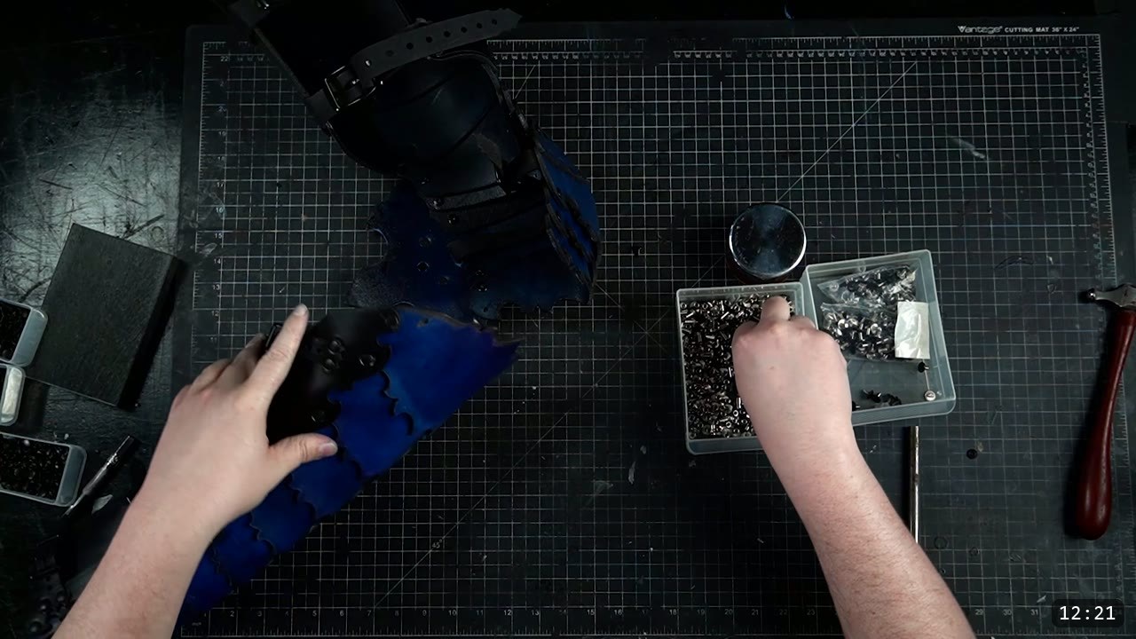 Leather Leg Armor Build Guide: Articulated Cuisses, Knees, and Greaves 14 hands fitting a black articulated knee-and-lame stack to a royal-blue cuisse on the cutting mat, Chicago screw bins alongside