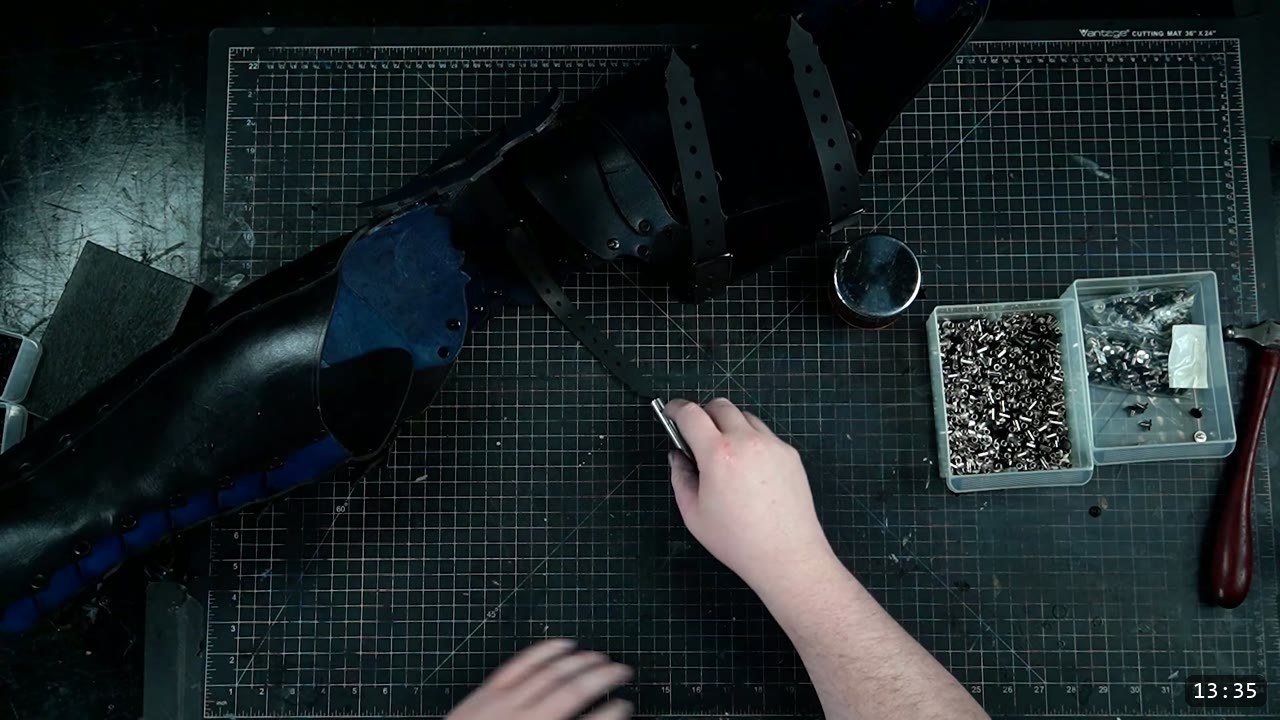 Leather Leg Armor Build Guide: Articulated Cuisses, Knees, and Greaves 3 a finished black leather leg armor with articulated knee lames and buckle straps, blue undertone showing at the edges, laid on a cutting mat