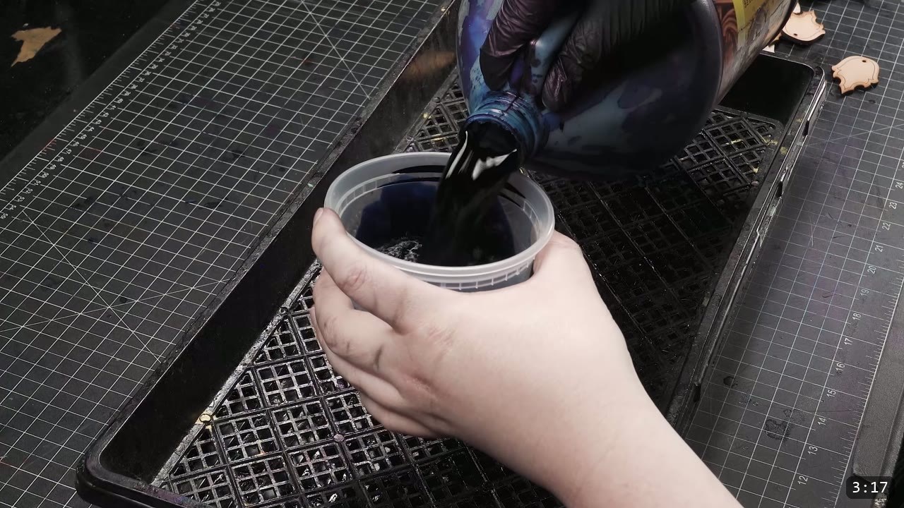 Leather Scale Skirting Build Guide: Laser-Cut Scales into a Modular Armor Skirt 7 a gloved hand pouring dark blue leather dye from a bottle into a clear plastic tub held over a black drip tray and cutting mat
