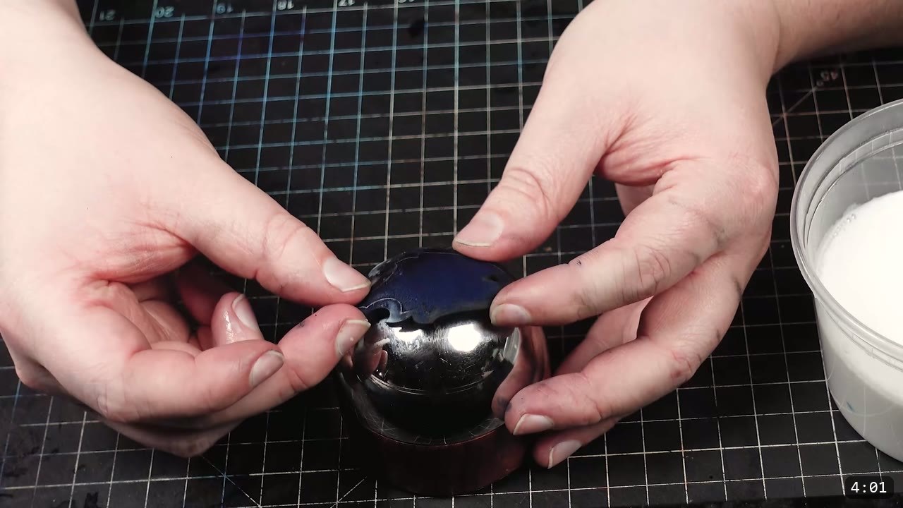 Leather Scale Skirting Build Guide: Laser-Cut Scales into a Modular Armor Skirt 8 both hands pressing a blue-dyed scale over a polished steel dome form on a cutting mat, a white tub of finish to the right