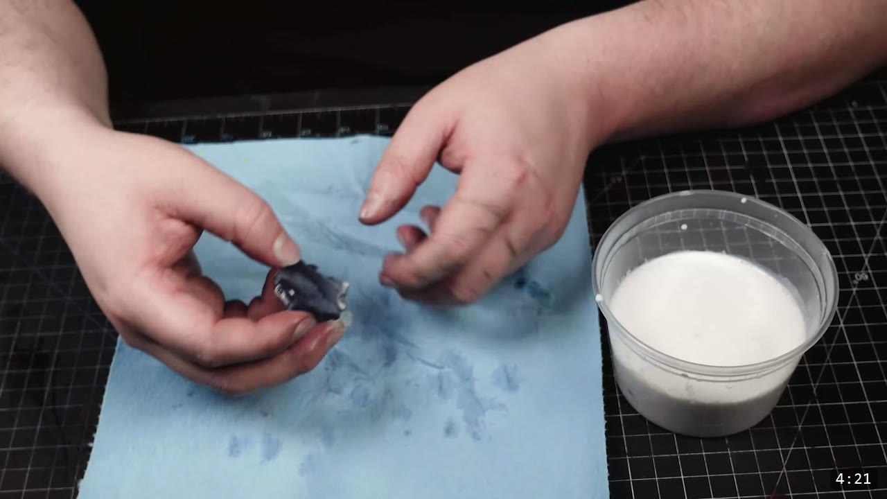 Leather Scale Skirting Build Guide: Laser-Cut Scales into a Modular Armor Skirt 9 hands hand-forming a single dark blue scale over a blue paper towel with a white tub of acrylic finish to the right