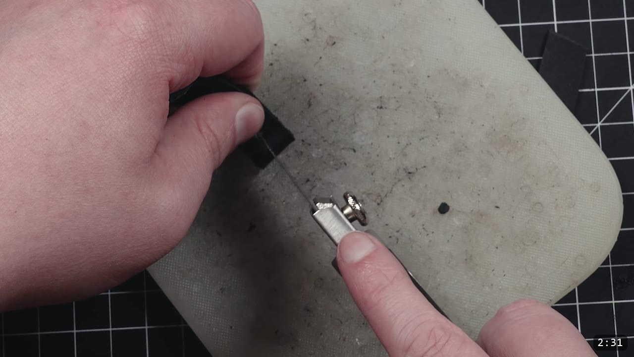 Leather Buckle Straps for Armor: A Reusable How-To with Free Patterns 6 close-up of a black strap end being worked with a slot tool and hardware on a poly cutting board