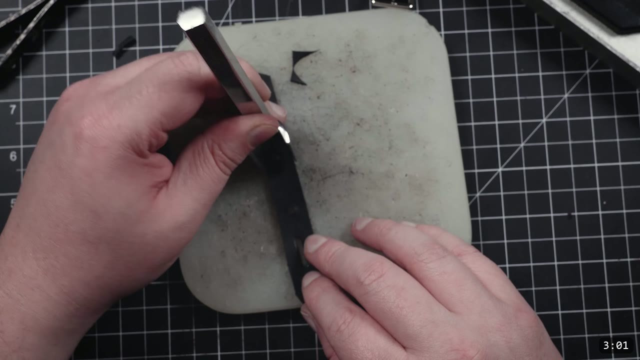 Leather Buckle Straps for Armor: A Reusable How-To with Free Patterns 7 running an edge tool along a black leather strap on a poly cutting board