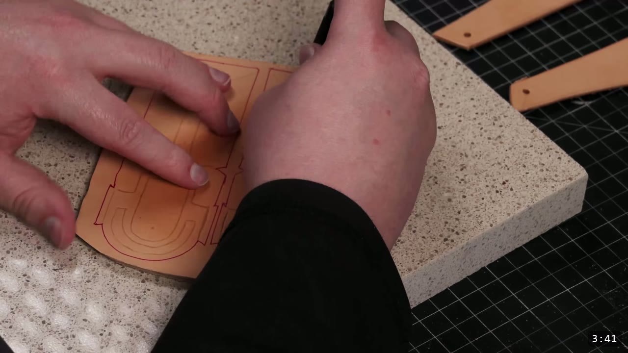 Leather Mandalorian Helmet Build Guide: Flat Pattern to Chrome Finish 4 transferring red design and reference lines onto a cut vegetable-tan helmet piece on a granite slab