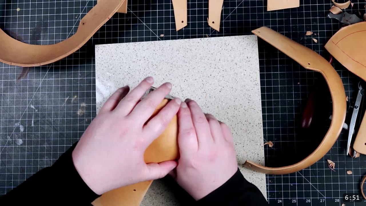 Leather Mandalorian Helmet Build Guide: Flat Pattern to Chrome Finish 5 shaping a damp vegetable-tan helmet core piece by hand on a granite slab, formed helmet halves resting nearby