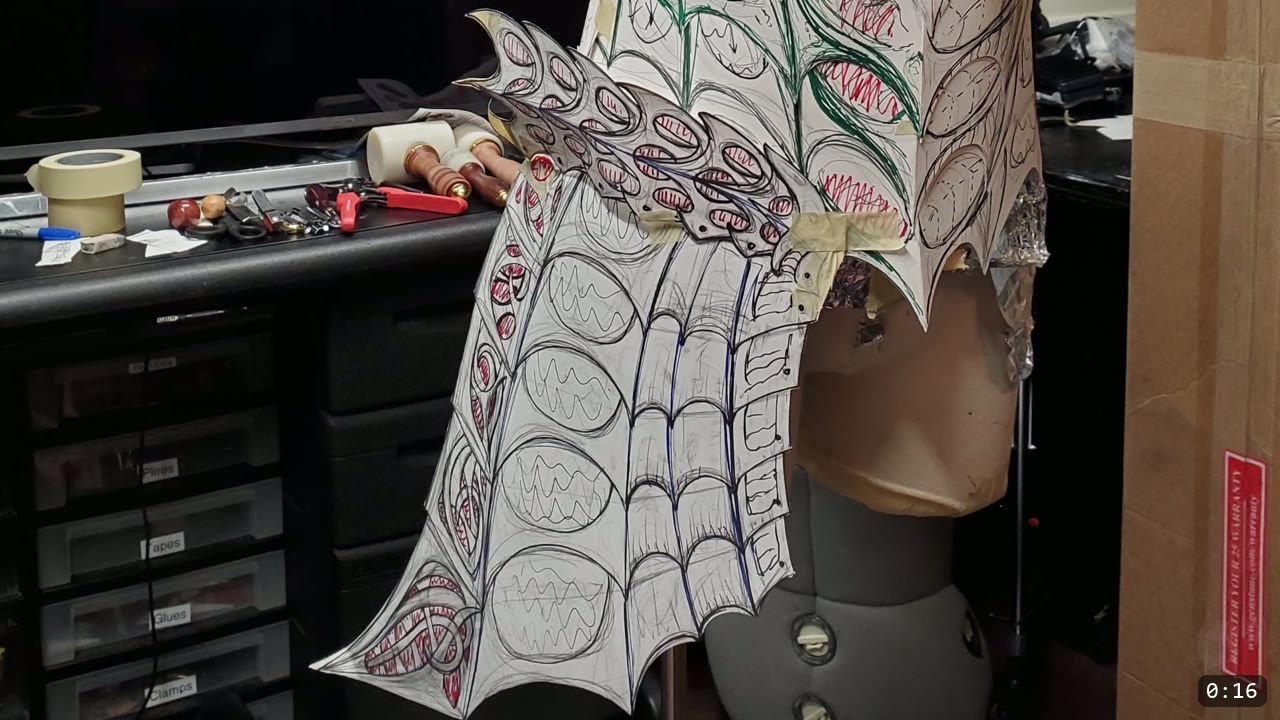 Custom Leather Armor: How I Design, Tool, and Color Test a Suit (Manticore Build) 2 paper armor pattern panels covered in hand-drawn filigree and geometric design lines, taped over a display form on the workbench