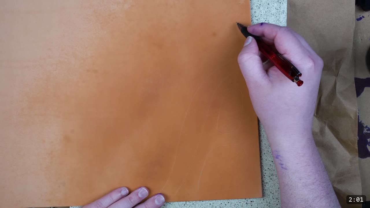 Custom Leather Armor: How I Design, Tool, and Color Test a Suit (Manticore Build) 3 a hand starting to freehand the armor design onto a square of natural vegetable-tan leather with a fine red-barreled pen