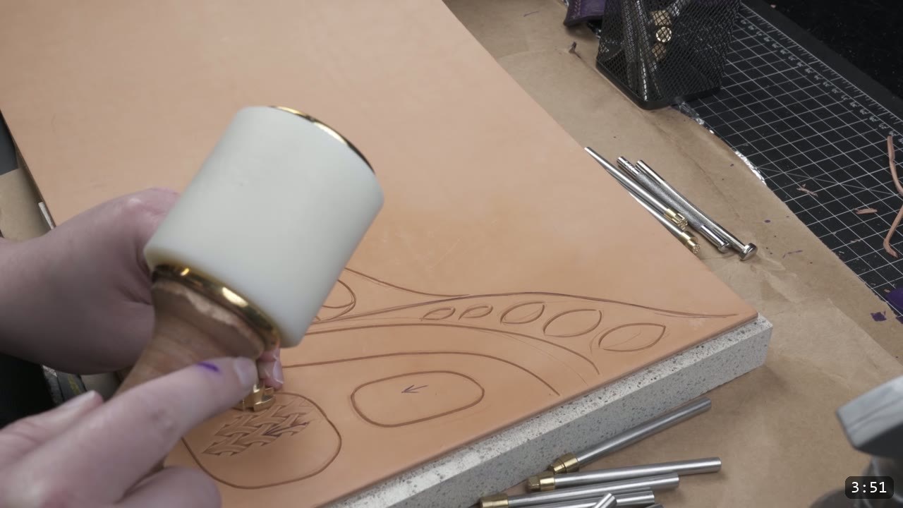 Custom Leather Armor: How I Design, Tool, and Color Test a Suit (Manticore Build) 6 a hand holding a stamp over the carved leather sample, with a row of steel bevelers and stamps laid out on the stone slab
