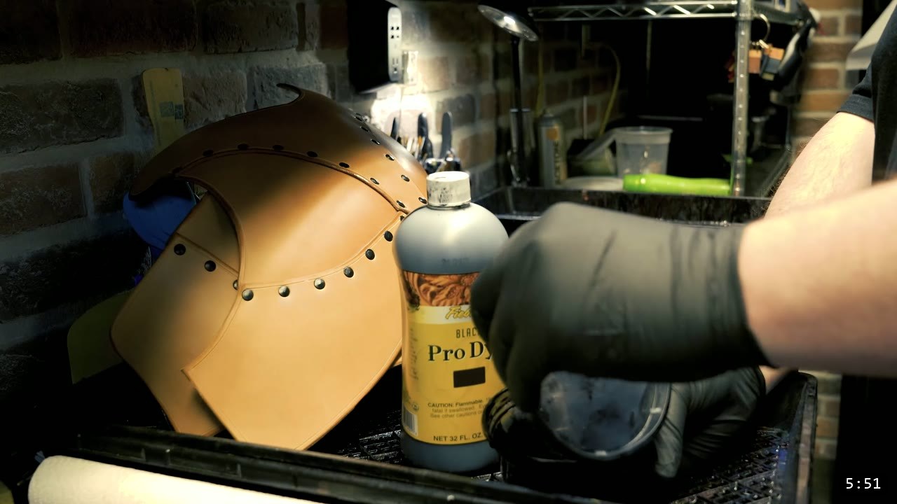 Female Leather Breastplate Build Guide: Warrior Armor from Cups to Buckles 10 a gloved hand mixing black leather dye beside a bottle of Pro Oil Dye and a tan riveted breastplate section