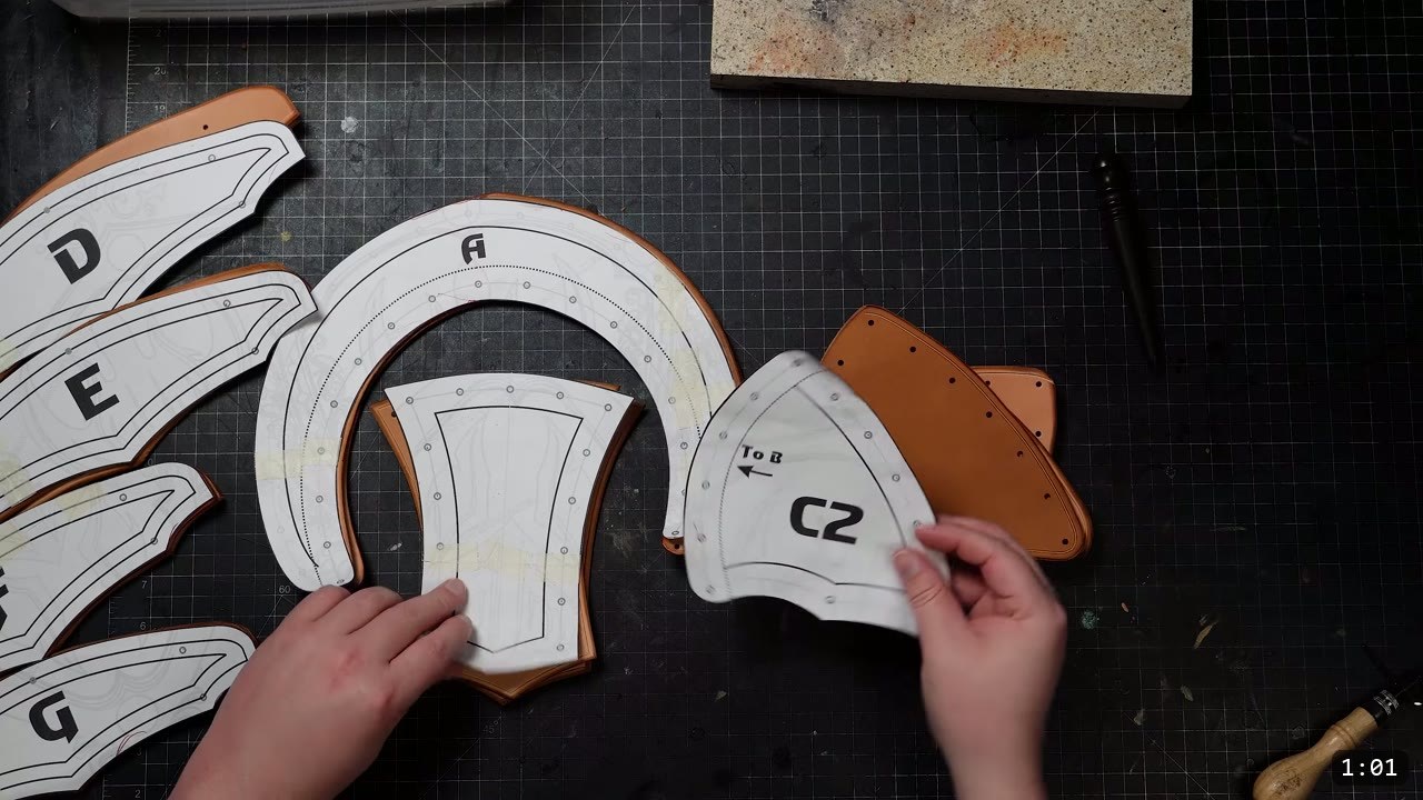 DIY Leather Pauldrons: A Beginner Build for Warrior Shoulder Armor 3 the cut pauldron pieces on the bench, each with its lettered paper pattern still attached and a "To B" orientation arrow marked on one piece